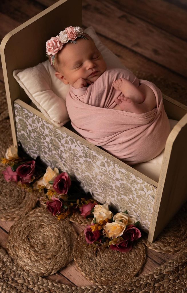 bébé emmailloté dans un lit décoré